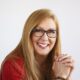 Smiling woman with glasses and clasped hands