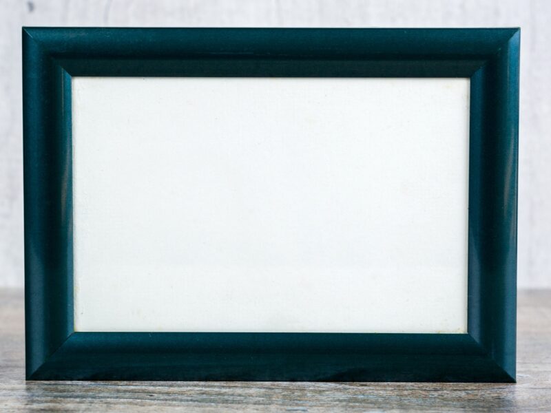 Blank teal picture frame on wooden surface